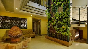 Un vestíbulo de diseño moderno, con una urna decorativa grande, un sofá y un jardín vertical.
