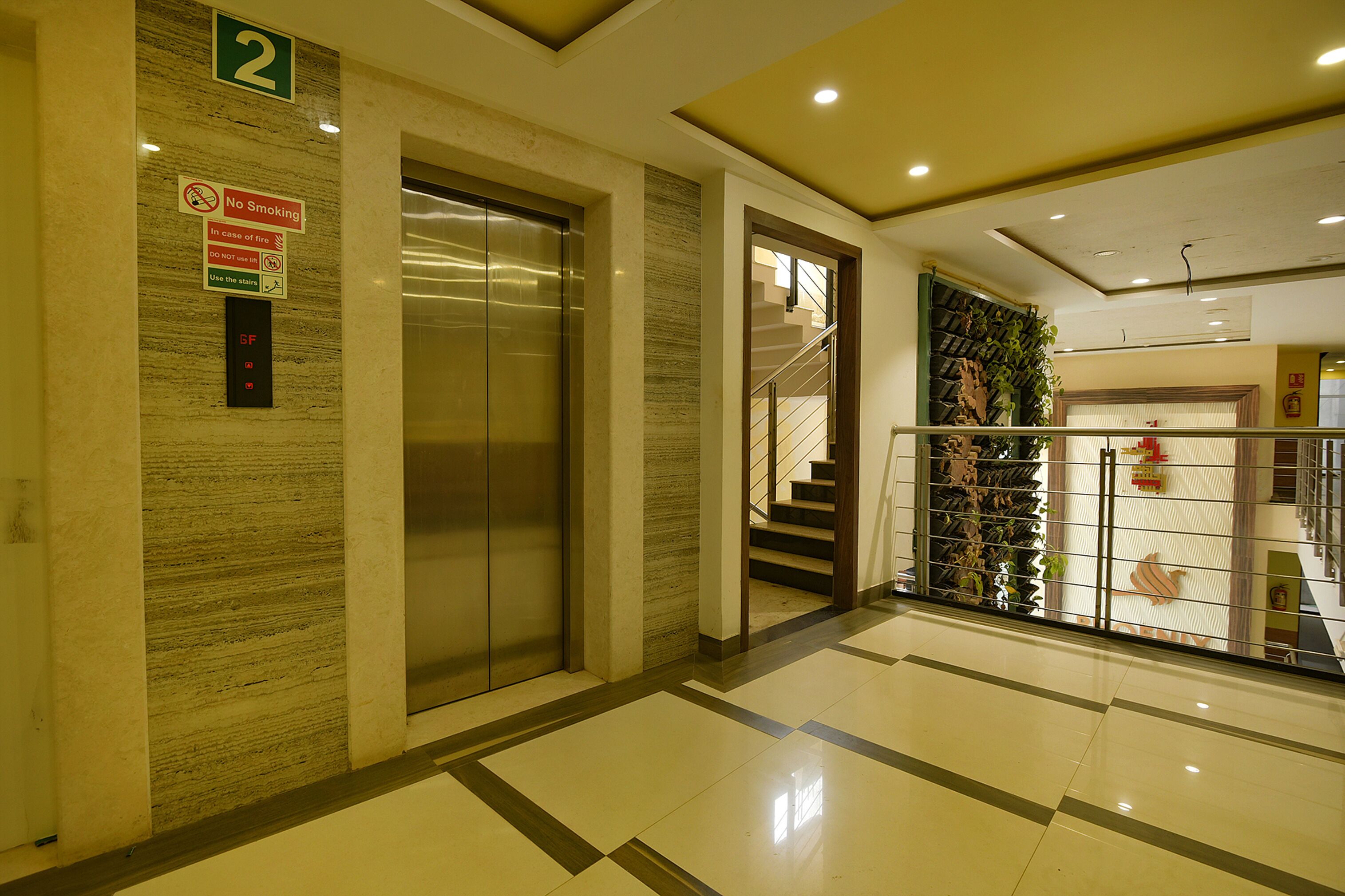 Corredor interno com elevador, escada e corrimão.