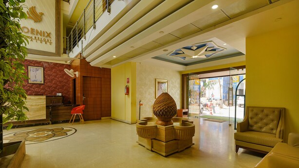 Un vestíbulo de hotel con una recepción, un gran jarrón decorativo y zonas de estar.