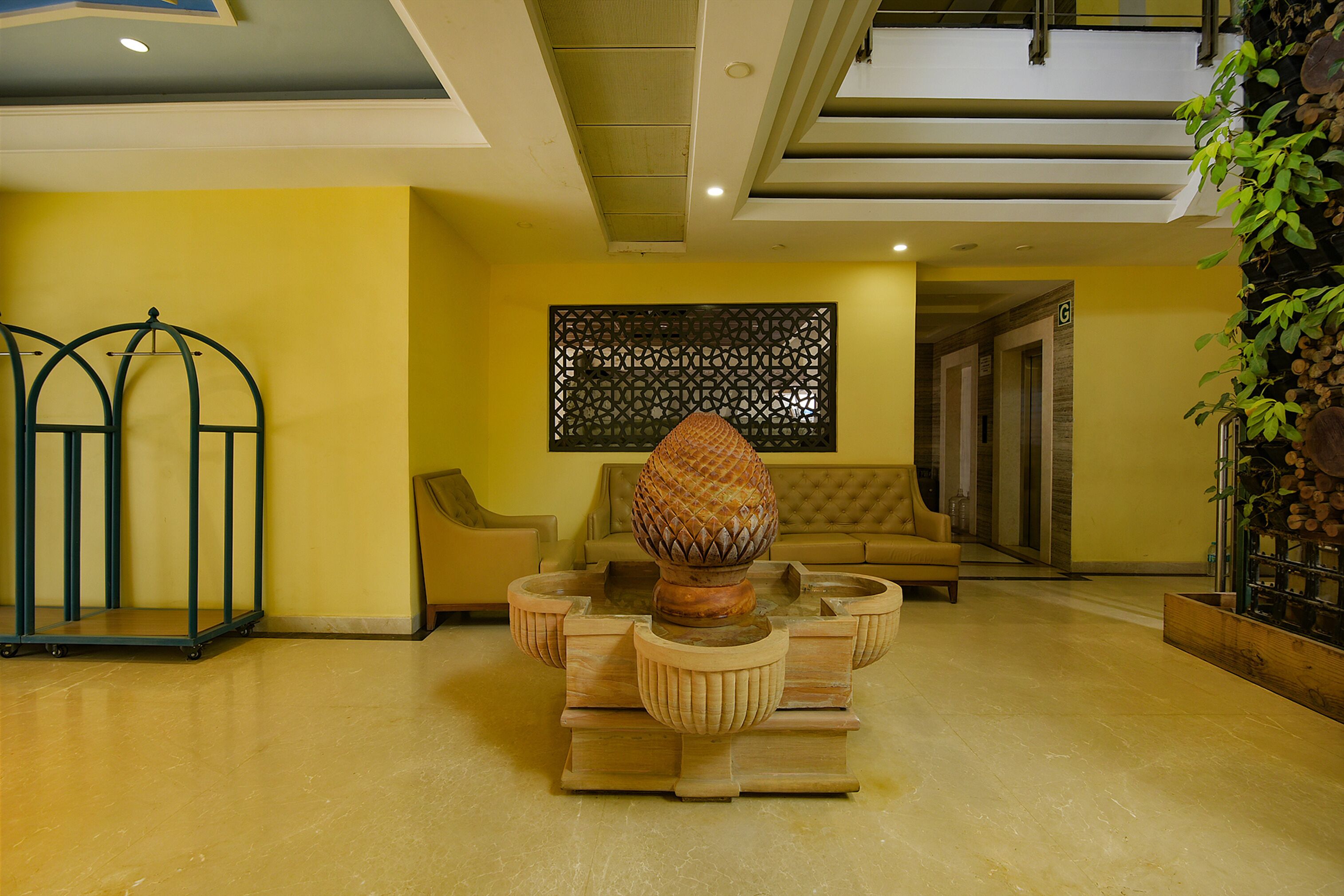 A lobby with a central wooden coffee table, a sofa, a decorative wall panel, and a staircase.