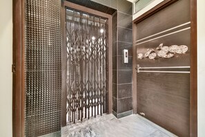Une entrée moderne avec un portail en métal, une porte en bois et un mur à texture.