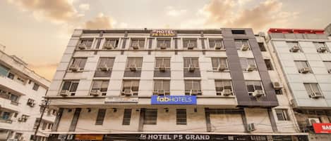 Un hotel de varios pisos con un cartel que dice 'fabHOTELS' y 'HOTEL PS GRAND'.