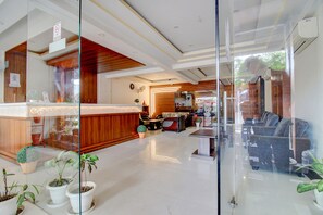 A reception area with a wooden reception desk, seating area with sofas, and potted plants. - Fabhotel Ps Grand (Lucknow)