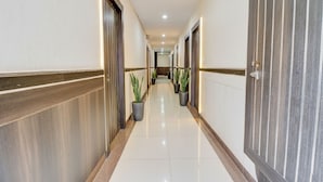 A hotel corridor with a polished floor, potted plants, and doors on both sides. - Fabhotel Ps Grand (Lucknow)