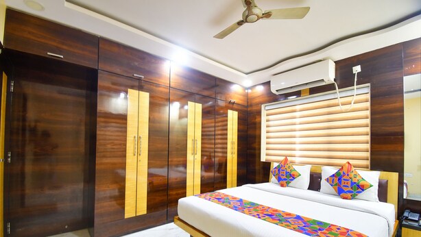 Habitación de hotel con una cama grande, armario de madera, ventilador de techo, aire acondicionado y una ventana con persianas.