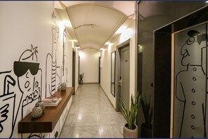 A hallway with a wooden bench, potted plants, and wall art. - Fabhotel Lord Inn (New Delhi)