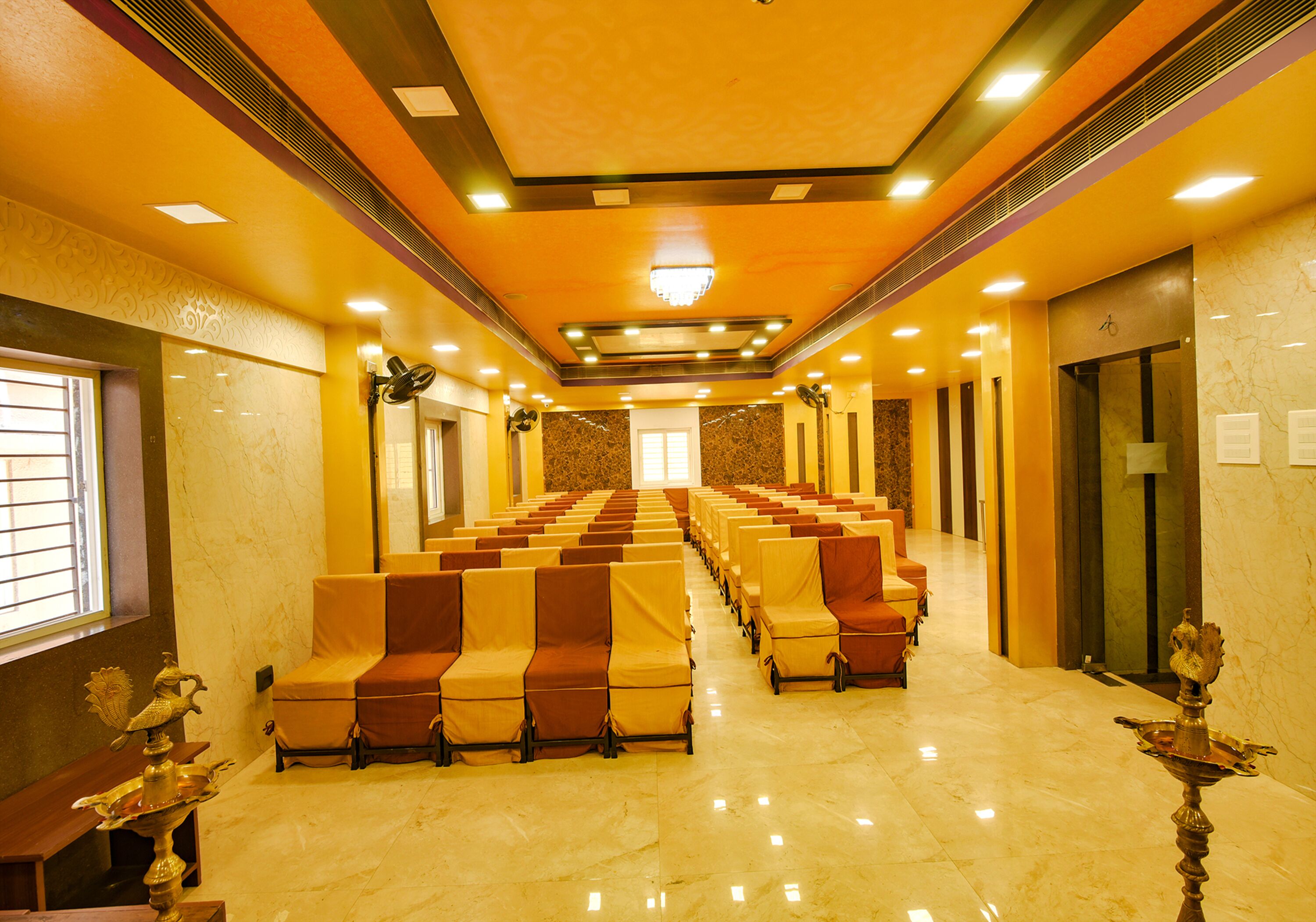 A hotel lobby with rows of seating, a chandelier, and a marble floor.