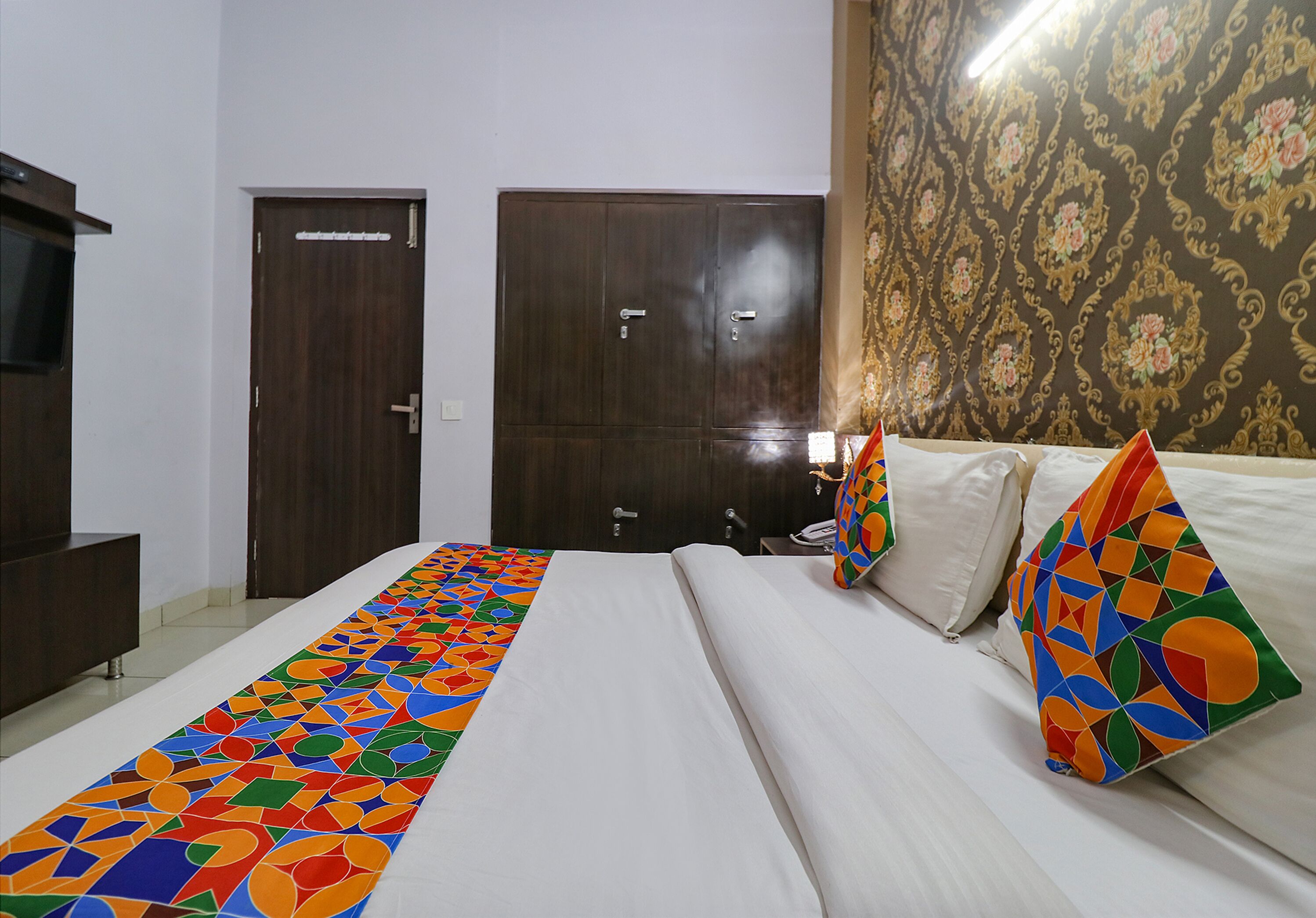 A hotel room with a bed, a wardrobe, and a television.
