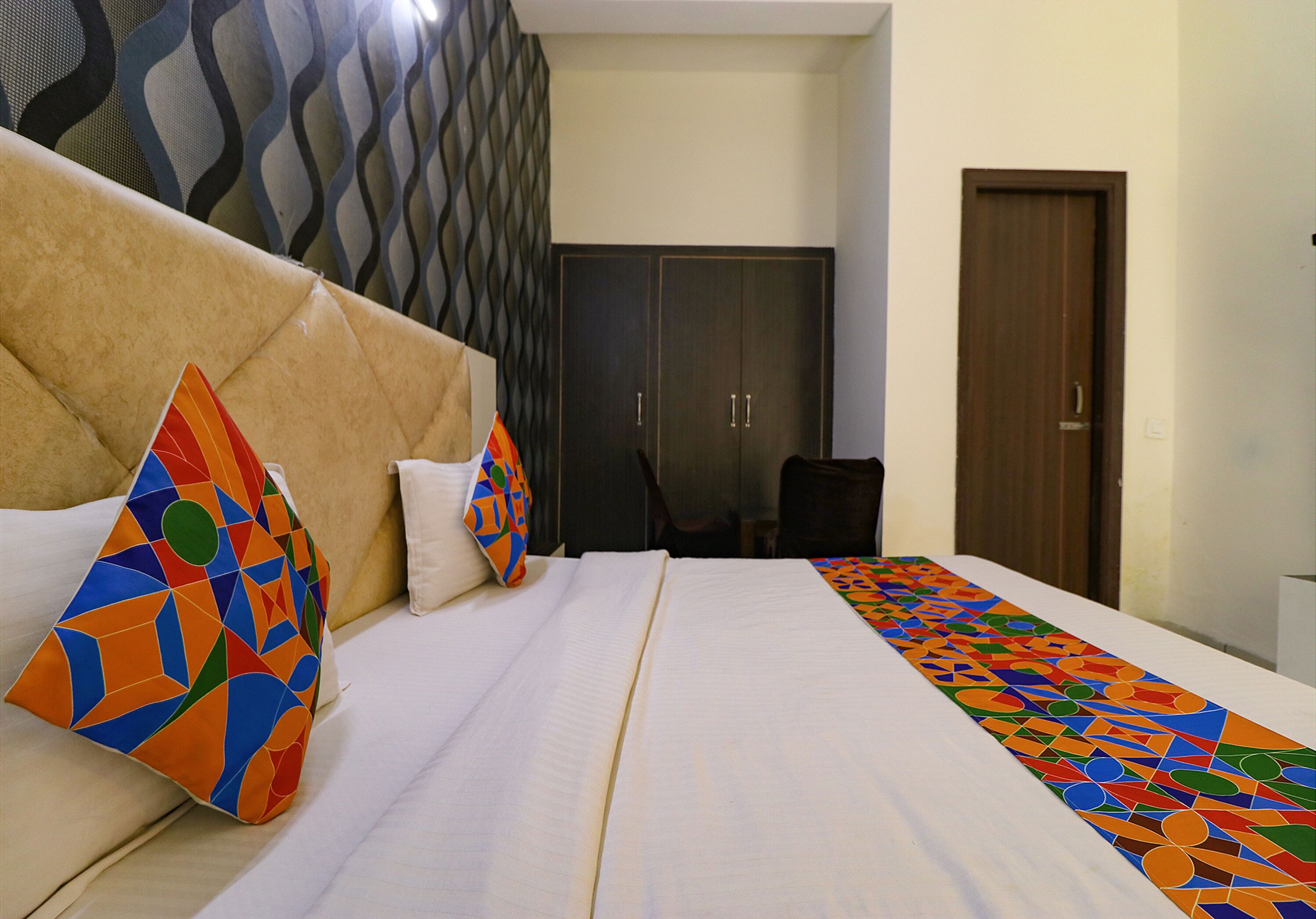 Una habitación de hotel con cama, almohadas, armario y puerta.