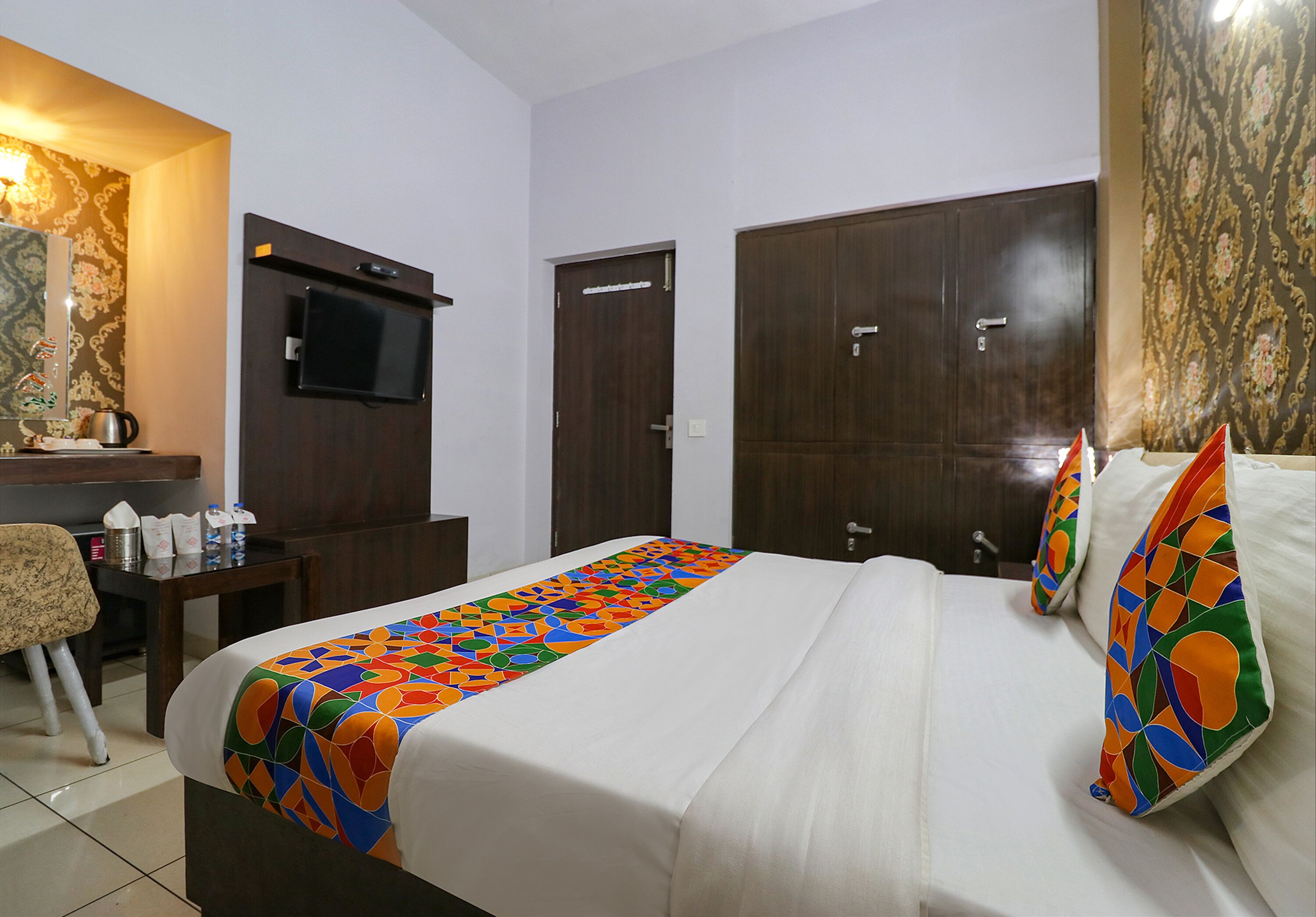 A hotel room with a bed, a desk with a TV, and two wardrobes.