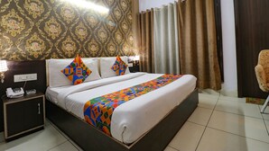 Une chambre d’hôtel avec un grand lit, une table de chevet avec un téléphone et un papier peint à motifs.