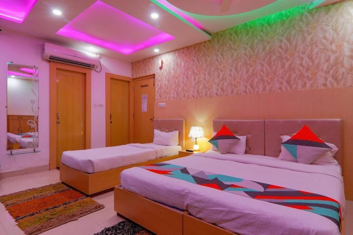 A hotel room with two beds, a mirror, a bedside table with a lamp, and a patterned wall.
