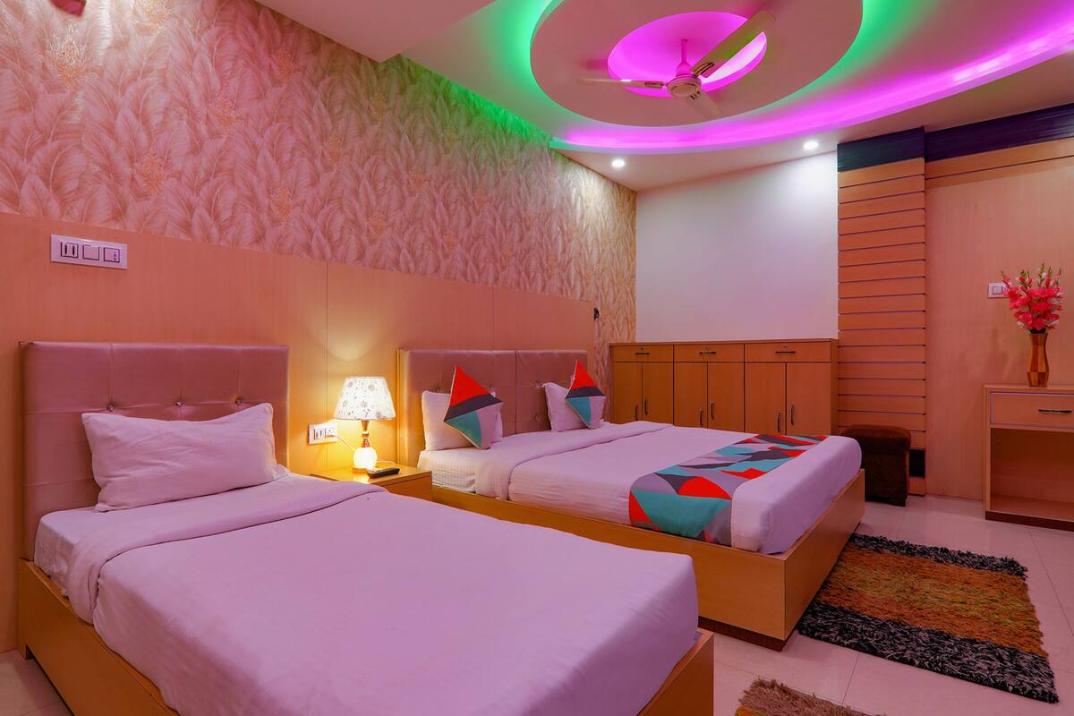 A hotel room with two beds, a ceiling fan, and a decorative wall.