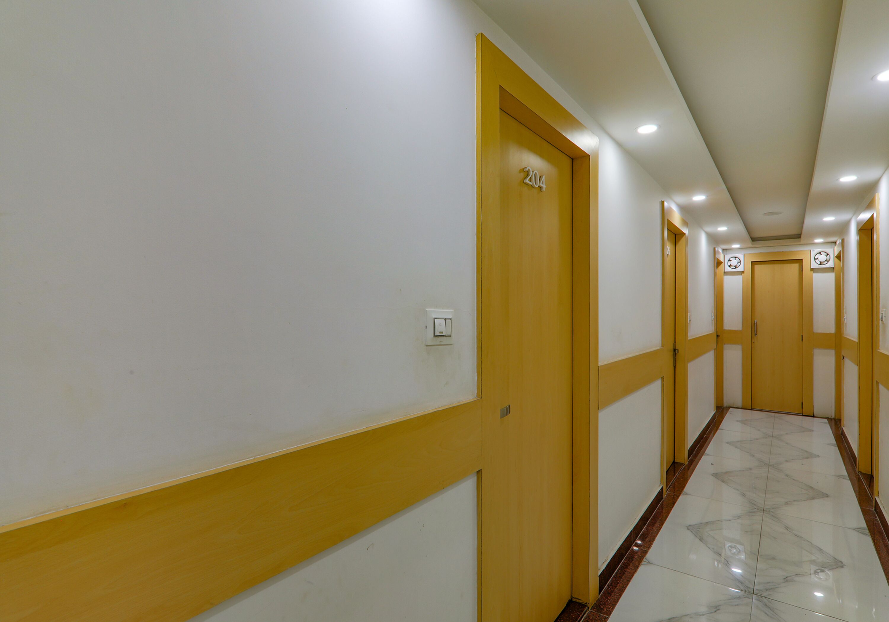 Un pasillo con puertas amarillas y paredes blancas, que conduce a varias habitaciones.