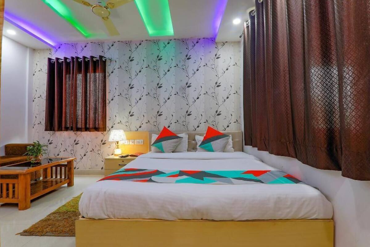 A bedroom with a bed, curtains, a nightstand, a lamp, and a ceiling fan.