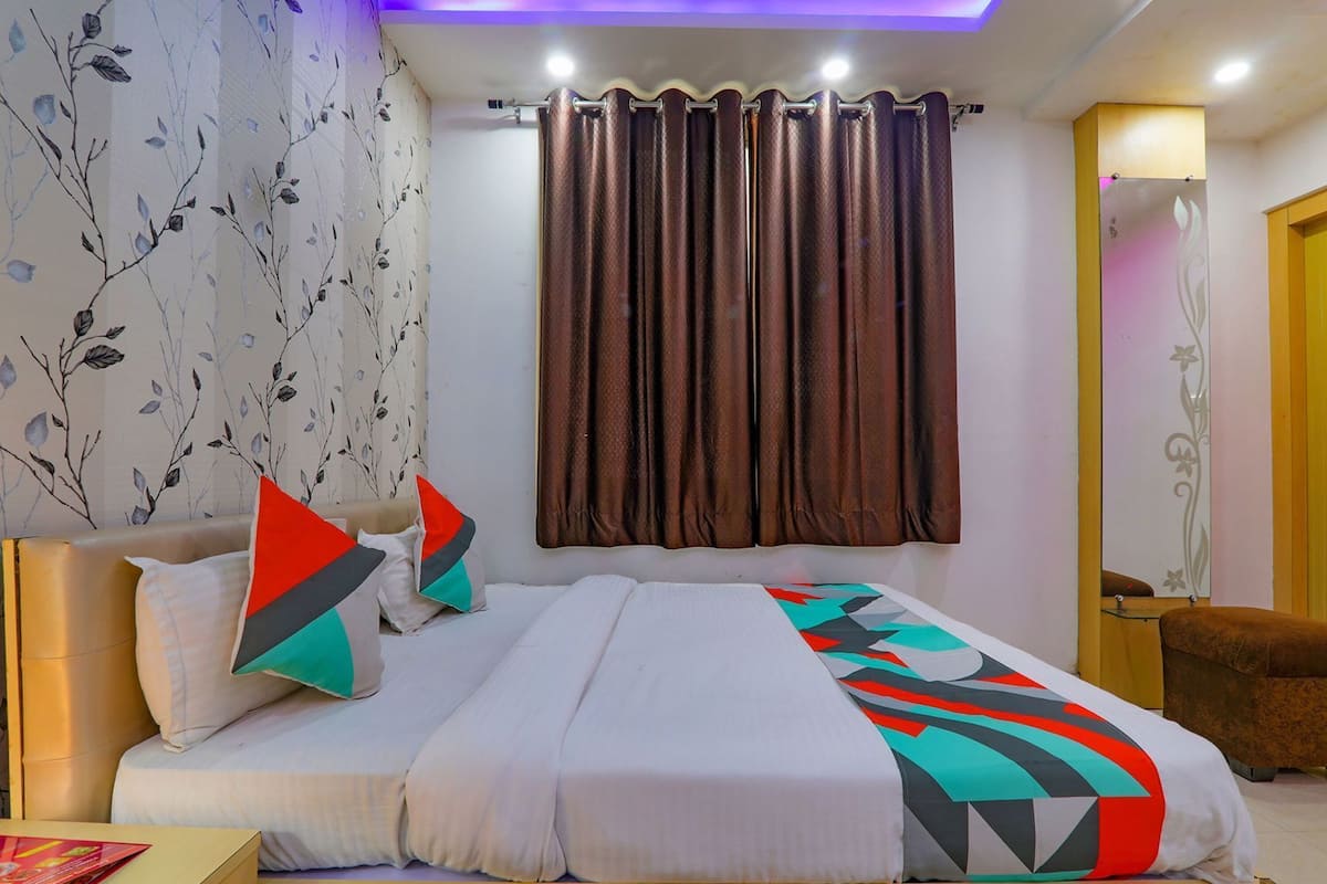 A bedroom with a bed, pillows, curtains, and a nightstand.