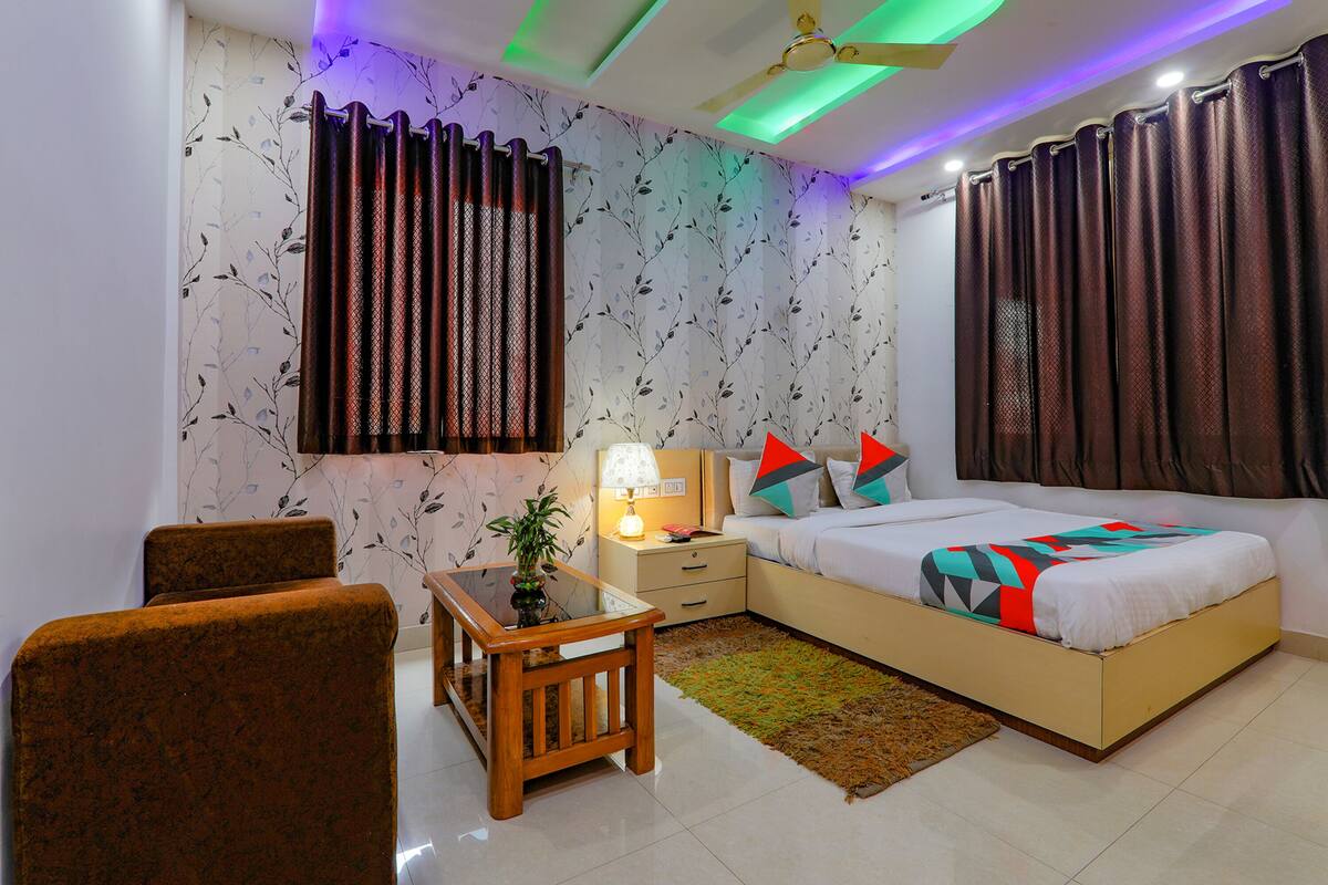 A bedroom with a bed, nightstand, lamp, chair, and a ceiling fan.