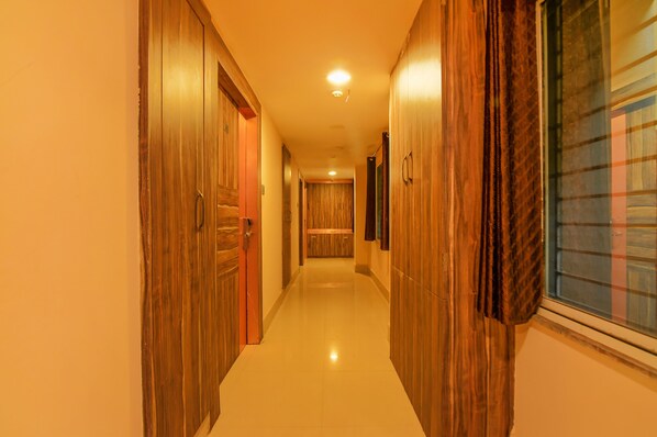 A hallway with wooden doors and a window on the right.