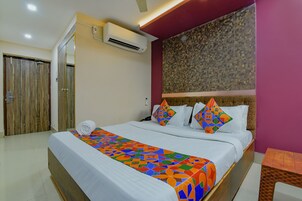 Habitación de hotel con una cama, un armario de madera, un equipo de aire acondicionado y una pared con textura.