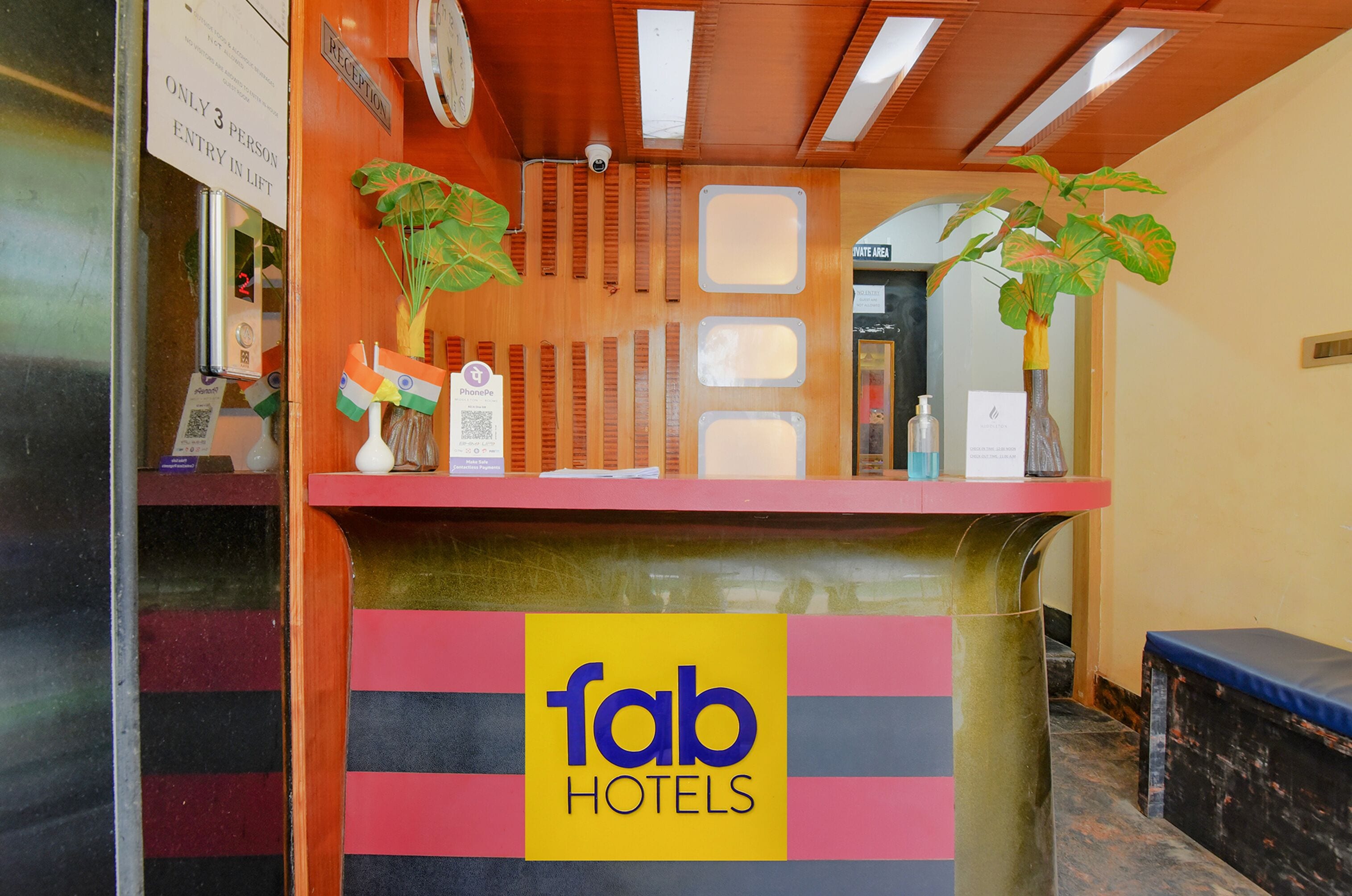 A reception desk with a 'fab hotels' sign, a lift button, and two potted plants.