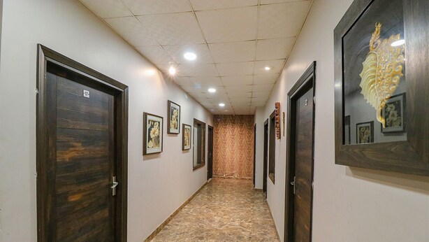 Un pasillo con puertas de madera oscura, obras de arte enmarcadas en las paredes y suelo de baldosas.