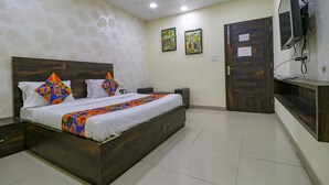 Un dormitorio con cama, televisor y obras de arte en la pared.