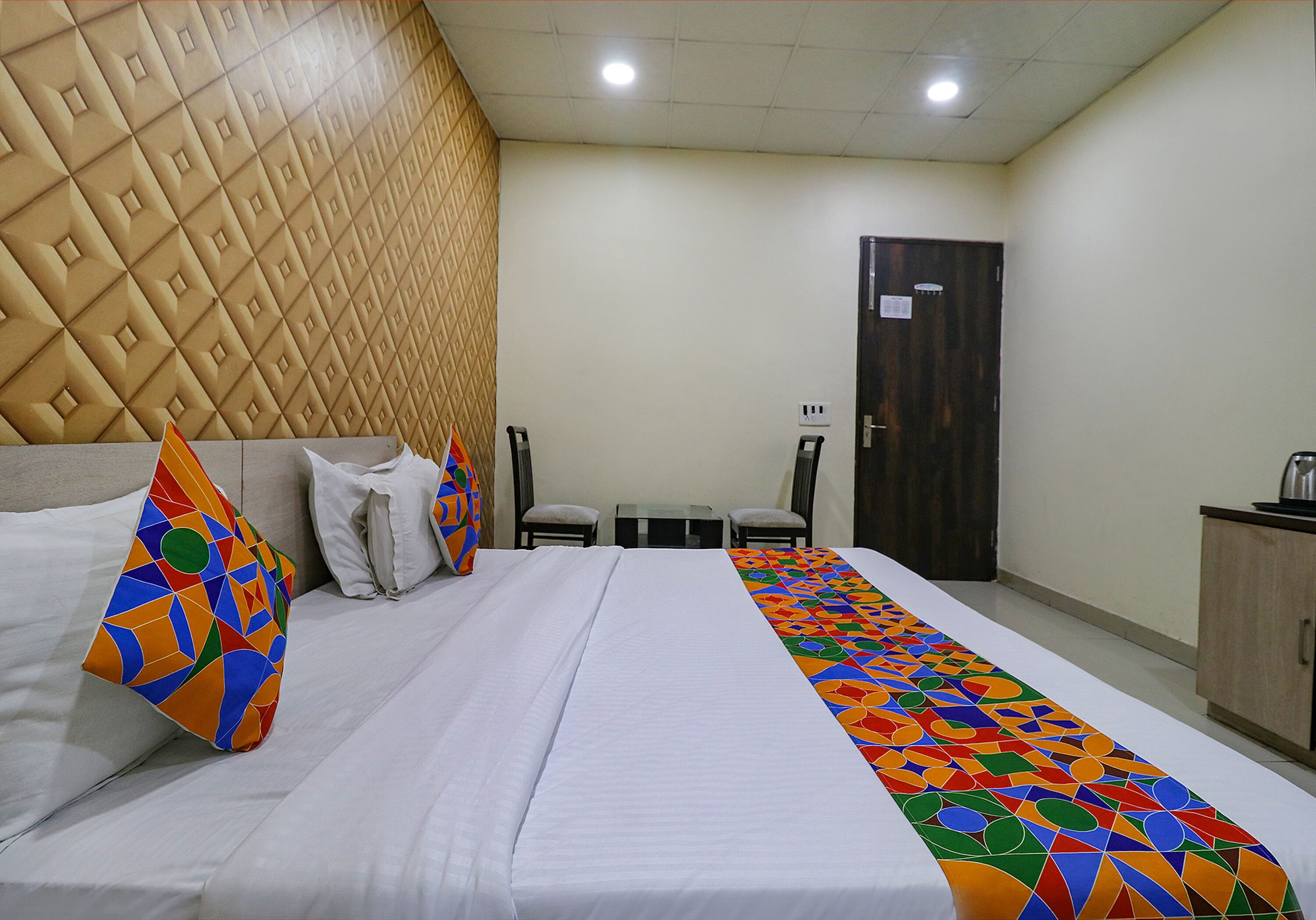 Une chambre d’hôtel avec un lit, des oreillers, une table, des chaises, une armoire et une porte.