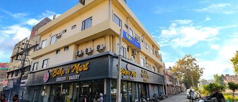 Un edificio de varios pisos con una panadería y una tienda de comestibles en la planta baja, y un cartel que indica un hotel en los pisos superiores.