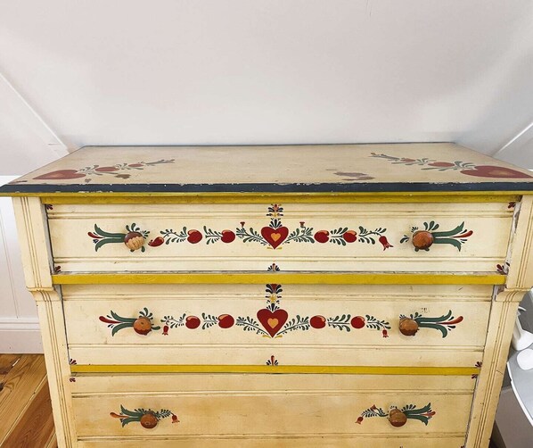 A vintage-style chest of drawers with decorative floral and fruit motifs.