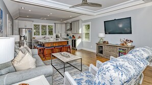 A spacious living room with a grey sofa, a coffee table, and a TV mounted on the wall. - Golf course views on Fort Holmes Trail overlooking hole number 10! Upper deck taking in island views (Bald Head Island)
