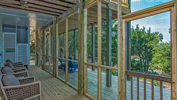 A covered outdoor area with wooden beams, large windows, and a view of greenery. - Golf course views on Fort Holmes Trail overlooking hole number 10! Upper deck taking in island views (Bald Head Island)