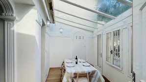 Een eethoek met een tafel voor vier personen, een houten vloer en een glazen plafond.