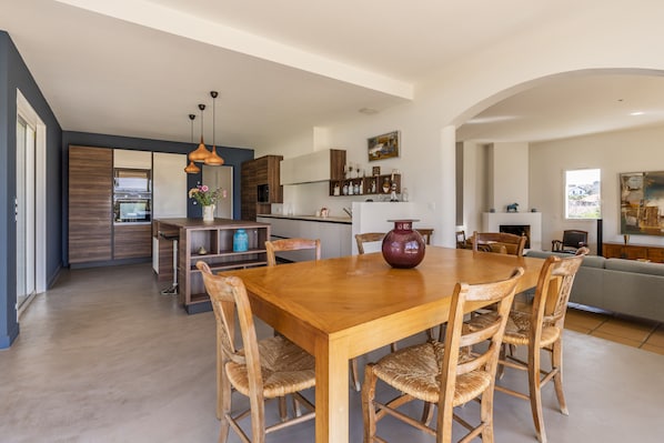 A spacious living area with a wooden dining table and chairs, a kitchen with modern appliances, and a cozy seating area with a sofa and fireplace.