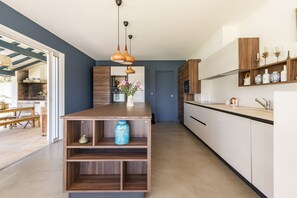 A modern kitchen with a central island, wooden cabinetry, and pendant lighting.