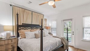 A bedroom with a four-poster bed, a ceiling fan, and a view of the outdoors through a door. - Playing Hooky! Dog Friendly- 4 Bikes- Heated Pool (Santa Rosa Beach)