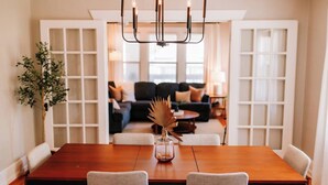 A dining area with a wooden table, two chairs, and a chandelier.