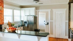 A modern kitchen with white cabinets, a stainless steel refrigerator, and a wooden countertop.