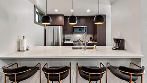 A modern kitchen with a large island, stainless steel appliances, and black pendant lighting. - Bear Claw 415 on Mountain Condo with Ski-In/Ski-Out Access! (Steamboat Springs)