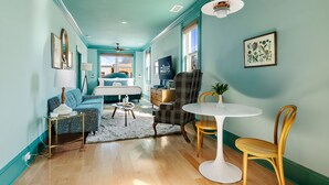 A room with teal walls, a bed, a desk, a chair, a table, and a lamp.