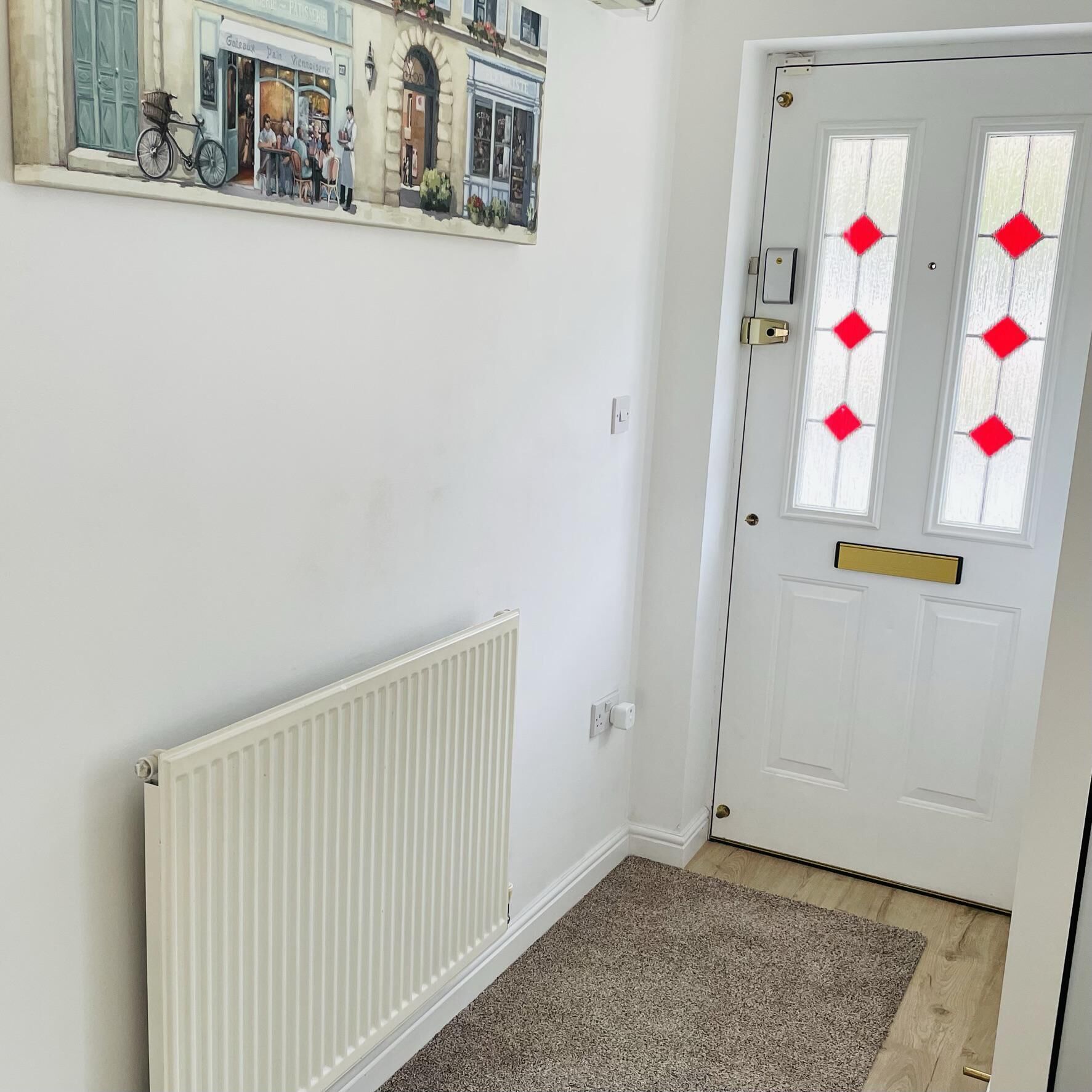 A hallway with a white door, a radiator, and a carpet.