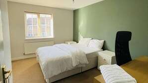 Una habitación de hotel con cama, escritorio, silla, ventana y radiador.