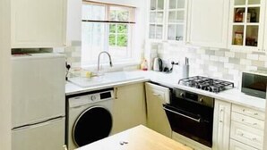 Una cocina compacta con lavadora, un lavamanos, estufa y microondas.