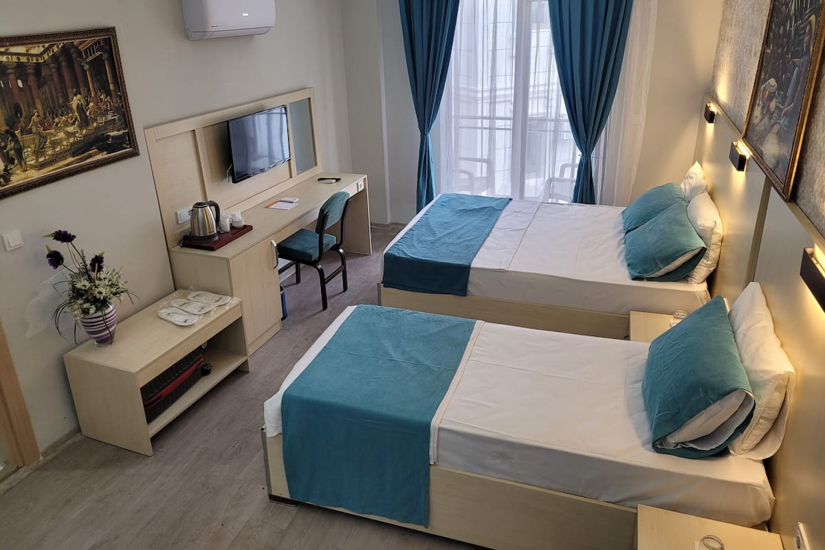 Habitación de hotel con dos camas, un escritorio, un televisor y un cuadro.