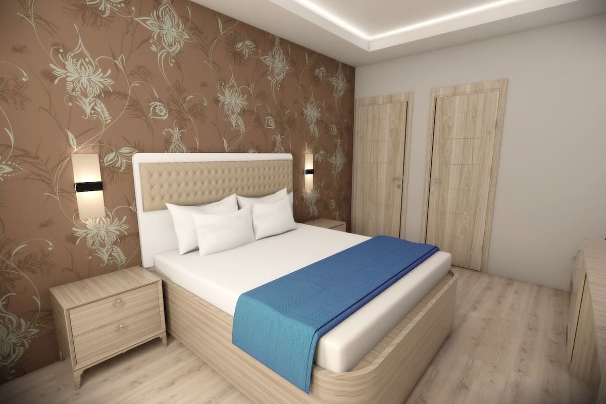 Un dormitorio con cama, mesita de noche, armario y luces fijadas a la pared.
