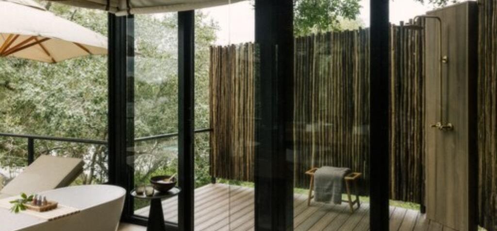 A balcony with a table and chairs, a wooden deck, and a view of greenery.