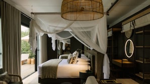 A bedroom with a large bed, bedside tables, a sofa, and a view of the outdoors. - Zambezi Sands By Batoka (Victoria Falls)