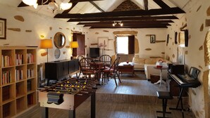 Een gezellige woonkamer met een tafelvoetbalspel, een piano en een bank.