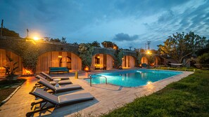 A swimming pool with lounge chairs, a brick archway, and a stone wall with plants. - Bona Me Yalıkavak (Bodrum)