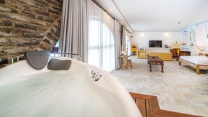 Ein modernes Hotelzimmer mit Steinwand, einer großen Badewanne, einem Holztisch und einem gelben Sofa.