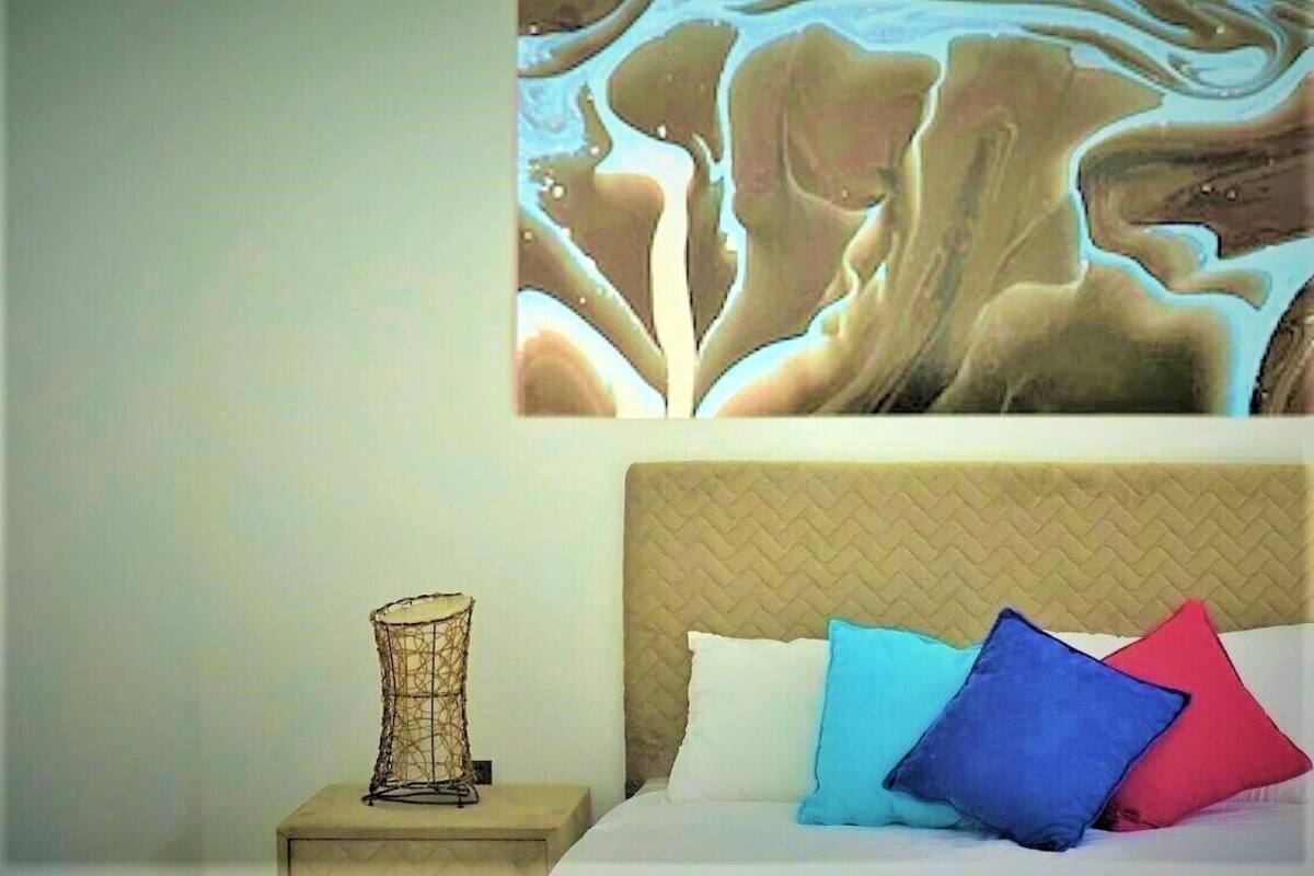 A bedroom with a bed, a nightstand, and a wall painting.